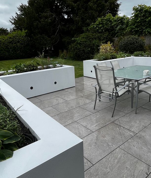 a white, marble patio in front of a small garden design